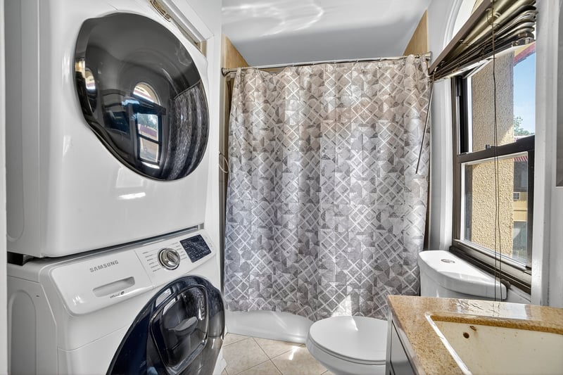 Bathroom featuring stacked washer and clothes dryer, vanity, light tile patterned floors, and a shower stall