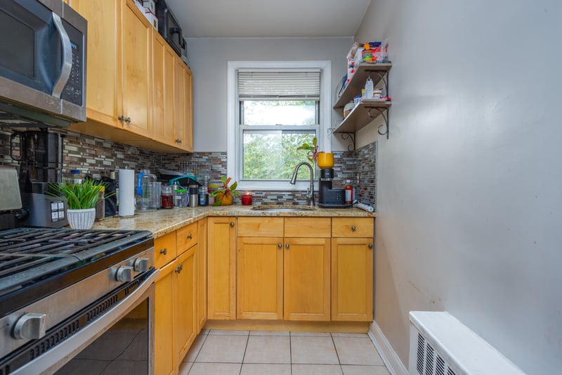 Kitchen with appliances with stainless steel finishes, backsplash, light tile patterned floors, open shelves, and light stone countertops