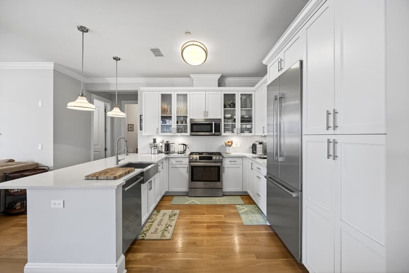 Kitchen featuring a peninsula, appliances with stainless steel finishes, decorative backsplash, glass insert cabinets, and pendant lighting...