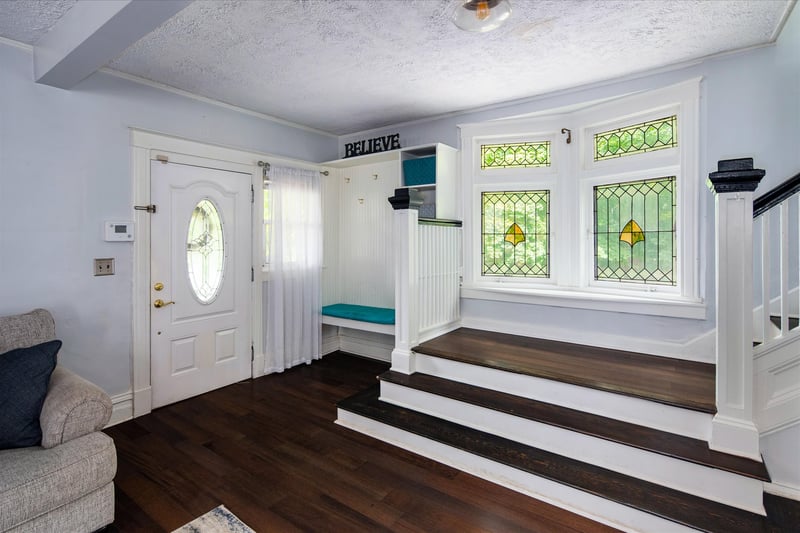 Foyer entrance with dropzone for coats, shoes, hats & gloves. Grand stairway with original stained glass windows.