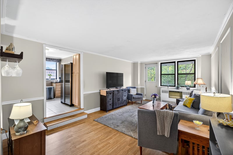 Sunken Living area with ornamental molding, light wood-type flooring, and radiator