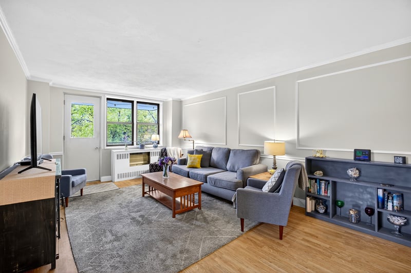 Living room featuring ornamental molding, light wood-type flooring, and a decorative wall