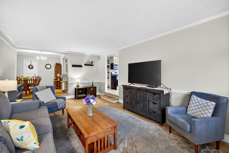 Living area with ornamental molding, wood finished floors, and a chandelier