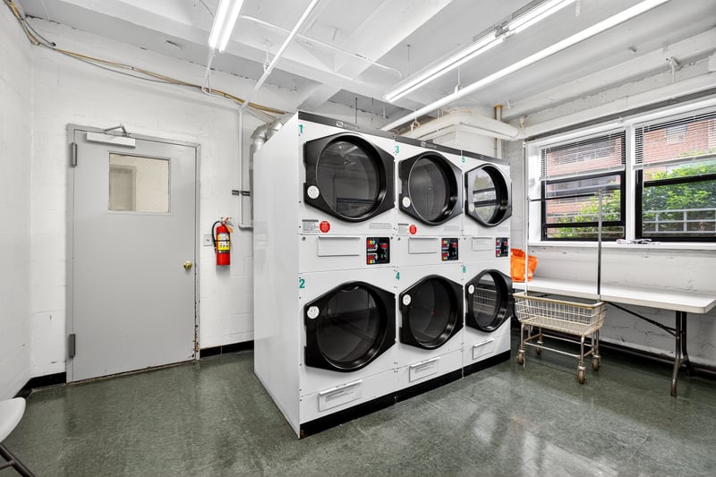 Community laundry room with concrete block wall, stacked washing machine and dryer, and independent washer and dryer
