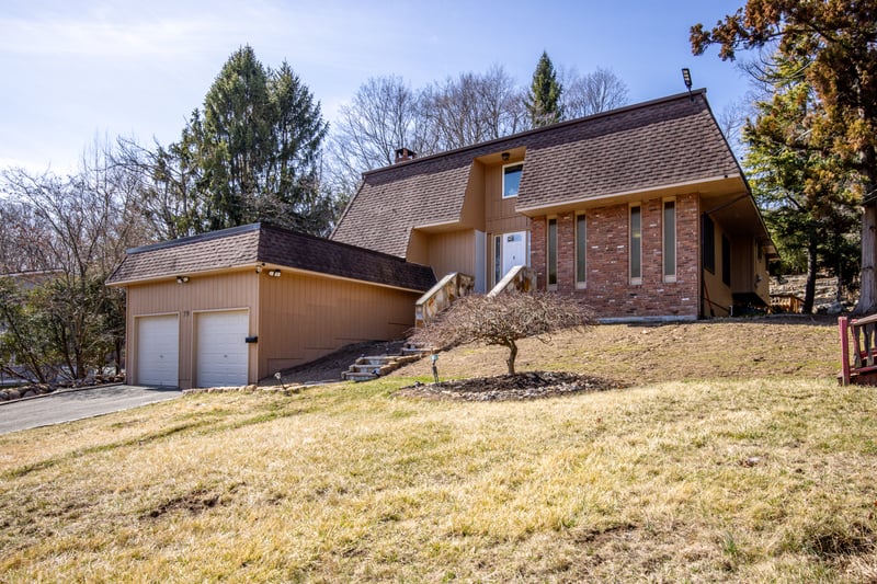 View of front of property featuring a shingled roof, mansard roof, and a front yard...