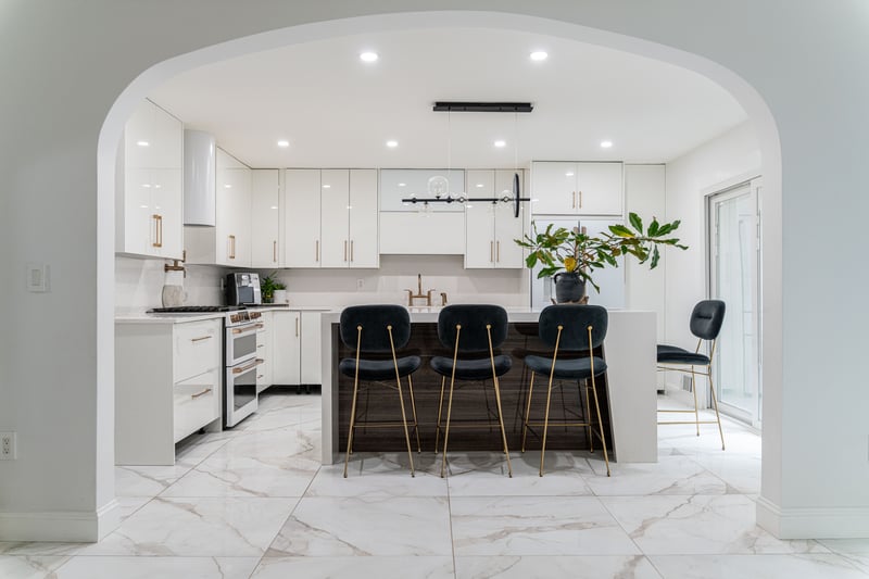 Kitchen with arched walkways, pendant lighting, white cabinets, a center island, and a breakfast bar area...