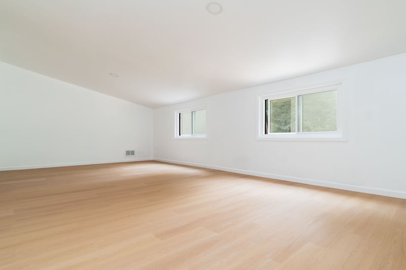 Spare room with plenty of natural light, light wood-type flooring, and vaulted ceiling