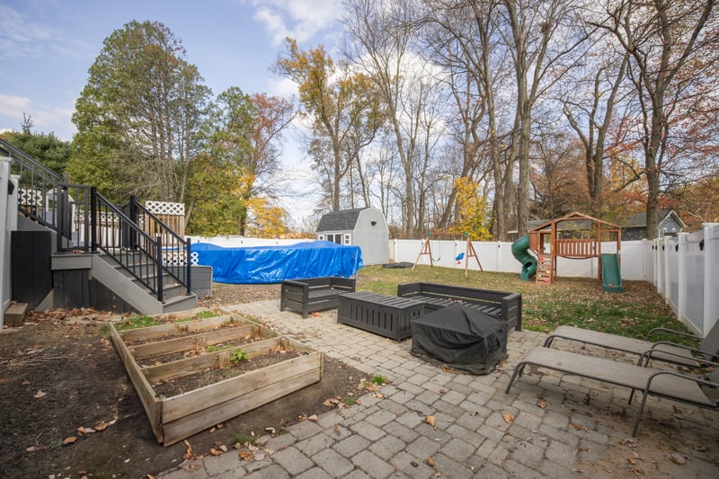 Fenced backyard with a garden, stairs, a patio, an outdoor structure, and a playground...