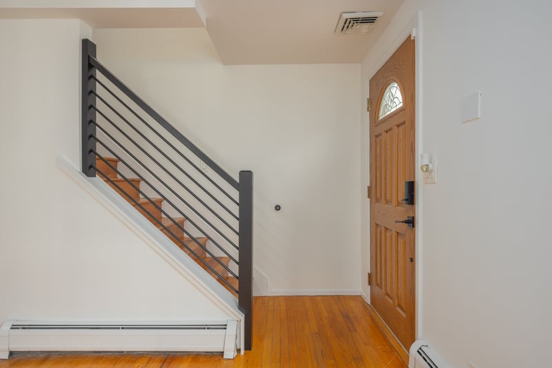 Foyer featuring light wood-type flooring, a baseboard heating unit, and stairs