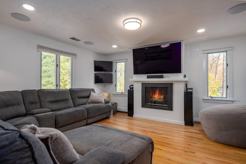 Living area featuring light wood-type flooring, plenty of natural light, a lit fireplace, and recessed lighting
