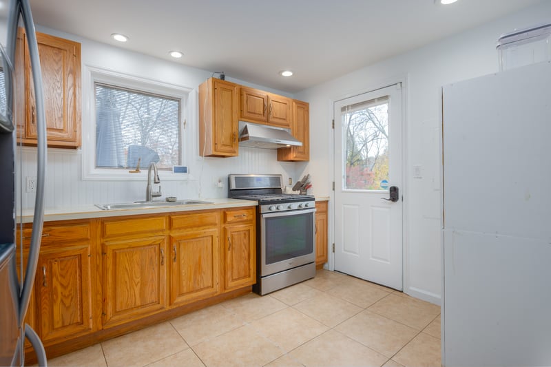 Kitchen with appliances with stainless steel finishes, light countertops, light tile patterned floors, under cabinet range hood, and recessed lighting