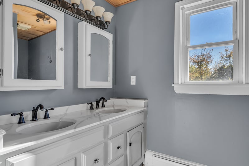 Shared full bath on upper level with double sink vanity and tub shower.