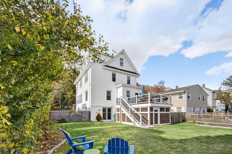 Back of house with a fenced backyard, and a wooden deck with storage space underneath.