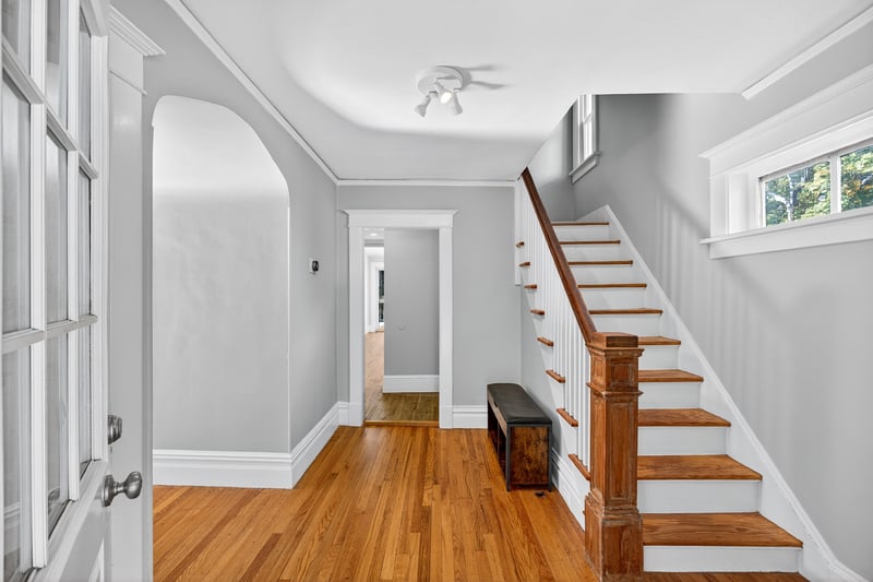 Entryway featuring arched doorways, hardwood floors, and stairway