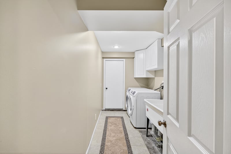 Laundry room on the lowest level with a utility sink and access to an additional storage room