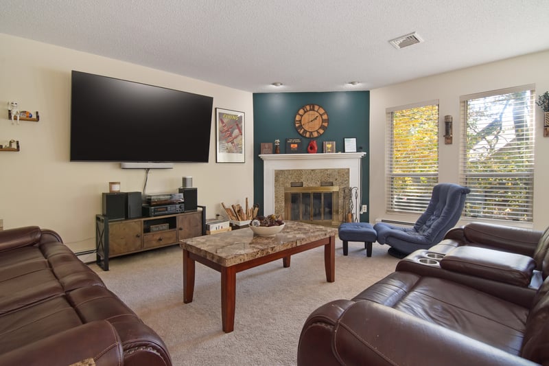 A welcoming living room showcases soft carpeting underfoot, a high-end fireplace as its focal point, a textured ceiling and baseboard heating for year-round comfort.