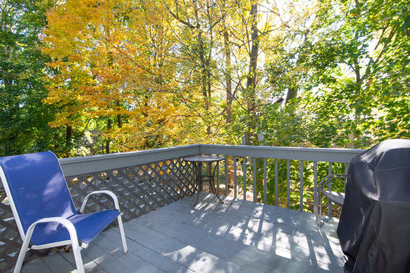 This spacious deck is framed by a canopy of mature trees and lush greenery.