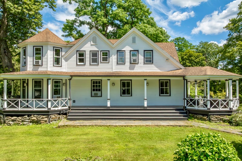 Back of house featuring a shingled roof, a lawn, and covered porch