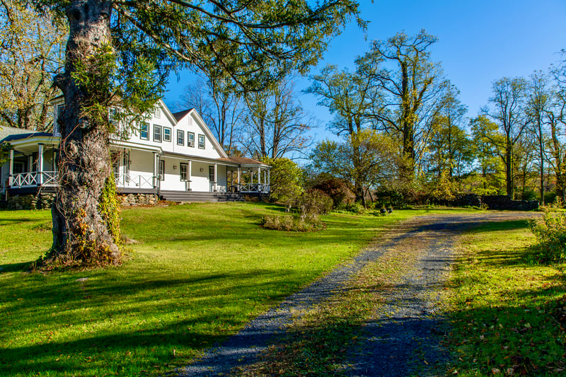 Farmhouse inspired home featuring a porch, driveway, and a front yard