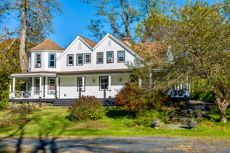 View of front of property with a porch, a chimney, and a front lawn