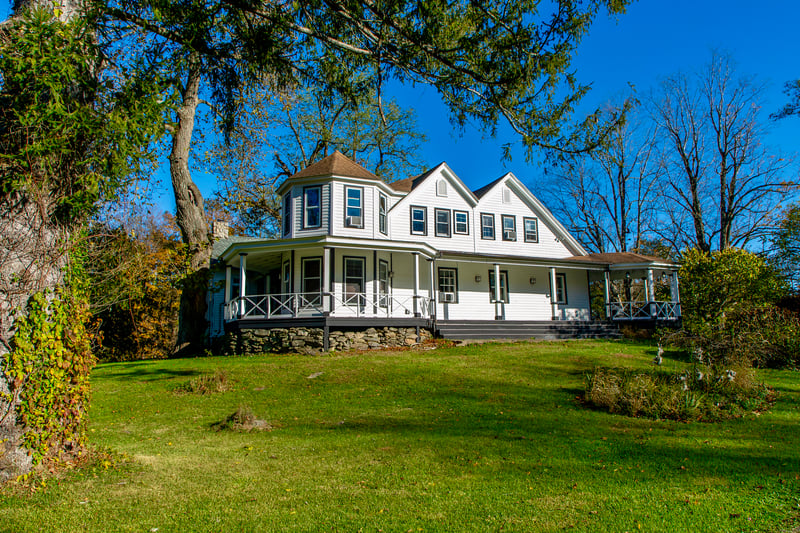 Victorian home featuring covered porch, a front lawn, and a shingled roof