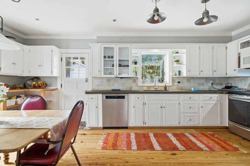 Kitchen with white cabinets, crown molding, glass insert cabinets, and light wood finished floors