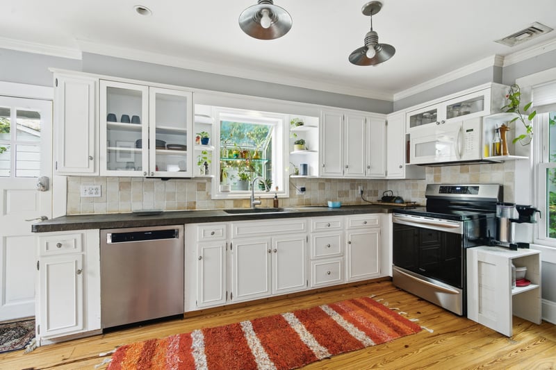 Kitchen featuring open shelves, glass insert cabinets, stainless steel appliances, white cabinetry, and plenty of natural light