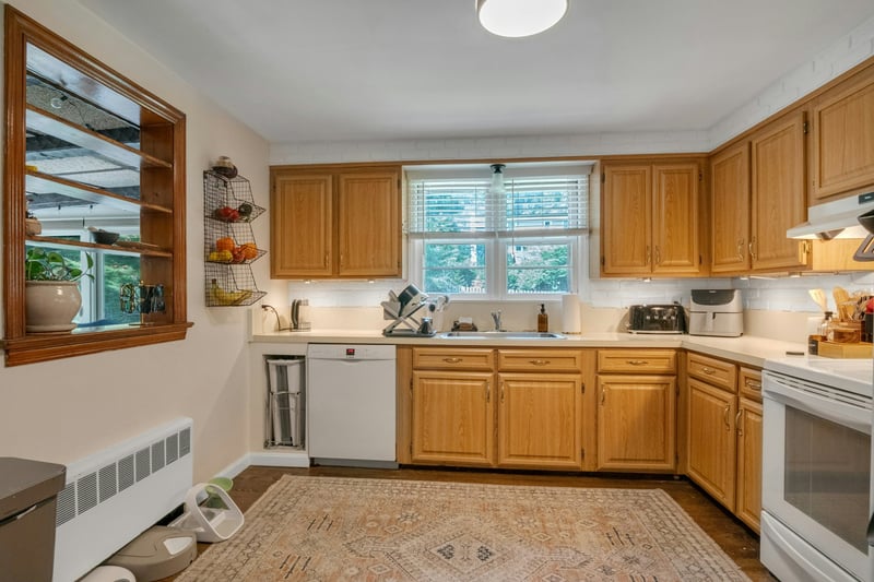 Kitchen with radiator heating unit, light countertops, white appliances, open shelves, and under cabinet range hood