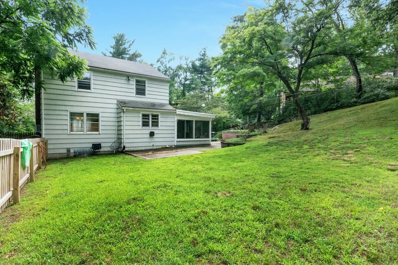 Rear view of house with a sunroom, a fenced backyard, and a shingled roof