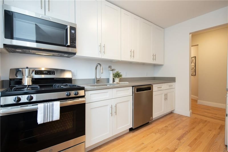 Kitchen with white cabinets, appliances with stainless steel finishes, light hardwood / wood-style floors, and sink