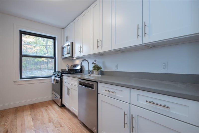 Kitchen with sink, white cabinets, light wood-type flooring, and appliances with stainless steel finishes