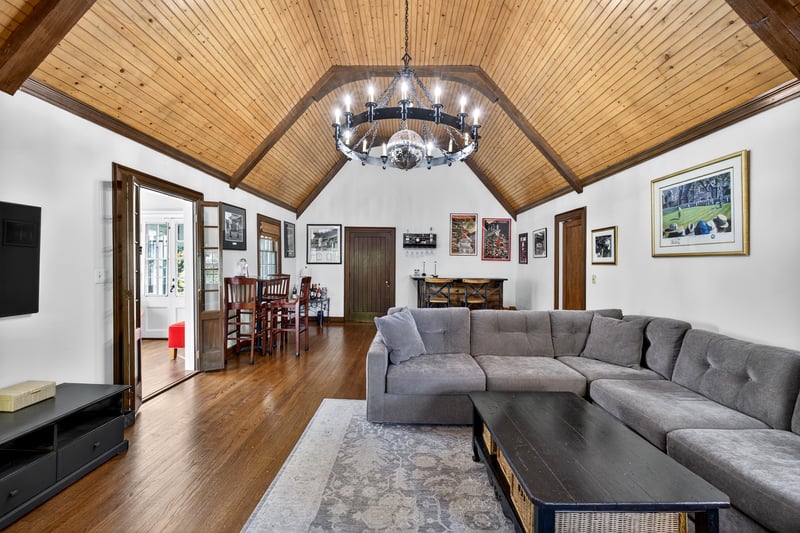 Living area featuring a wooden ceiling with exposed beams, high vaulted ceiling, dark wood-type flooring, and a chandelier