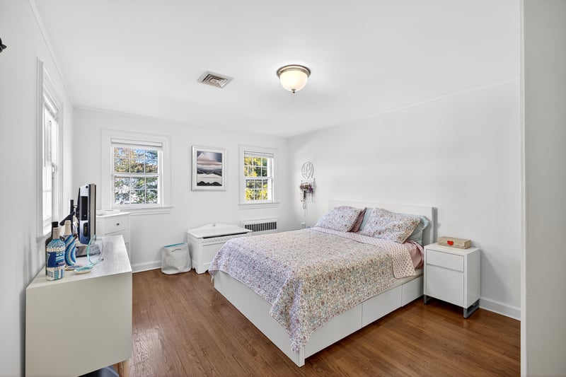 Bedroom featuring dark wood finished floors, crown molding, and radiator heating unit