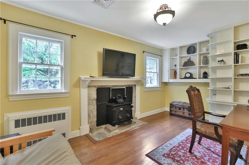 Home office on First floor with a wood stove, wood finished floors, radiator heating unit, and ornamental molding