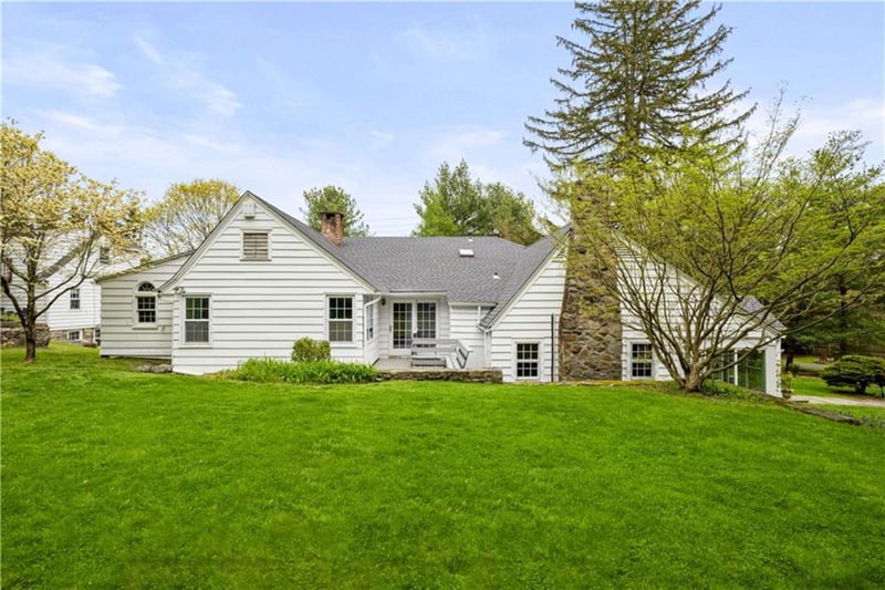 Rear view of house with a lawn, a chimney, and roof with shingles