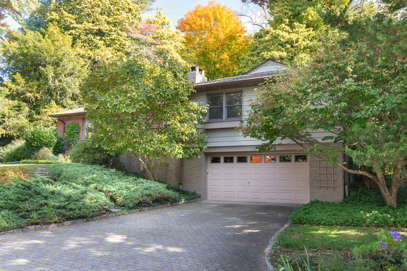 Oversized, stone paved driveway leads to generous 1+ car garage with abundant storage space