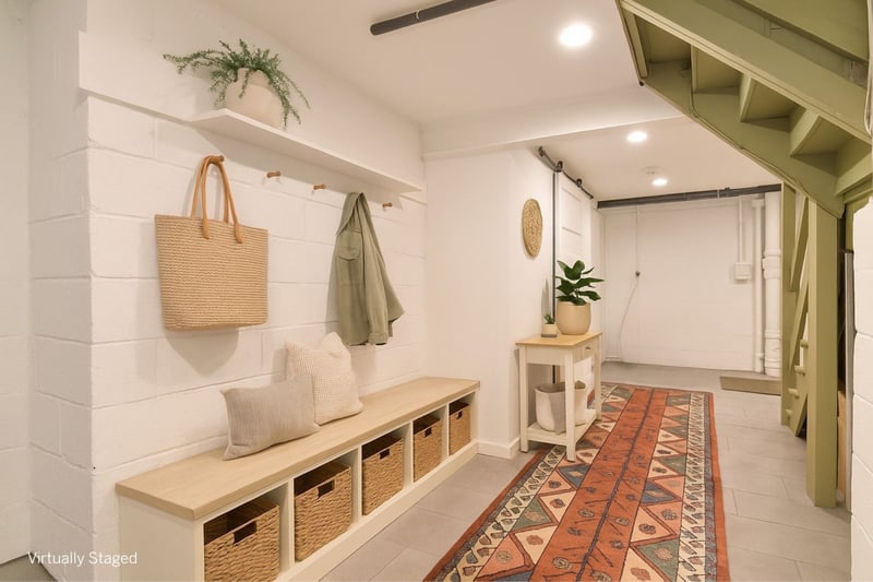 Virtually staged mudroom connects family to bedroom bath and laundry room with recessed lighting and barn style door.