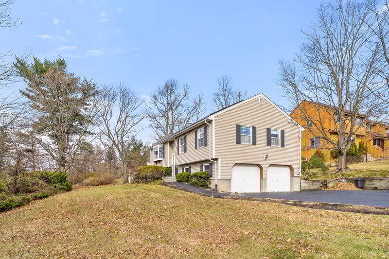 View of side of home with driveway, an attached garage, and a lawn