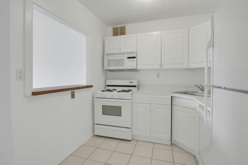Kitchen featuring white appliances, white cabinetry, light countertops