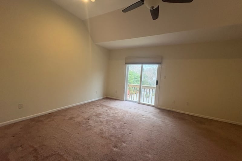 Carpeted spare room featuring high vaulted ceiling and ceiling fan