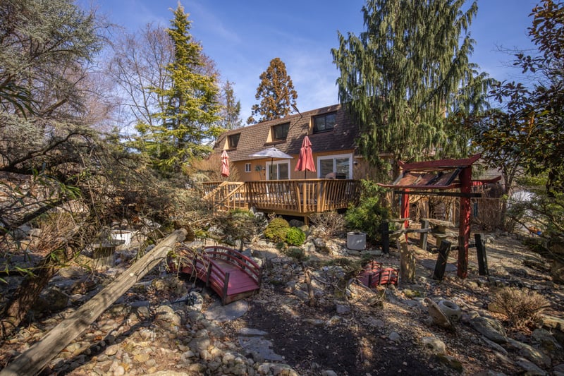 Rear view of property featuring mansard roof and a wooden deck