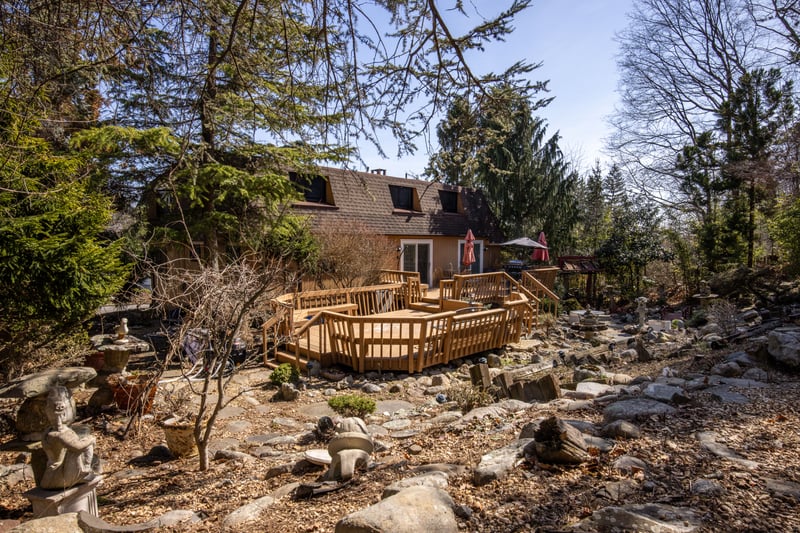 Rear view of house with mansard roof, a deck, and roof with shingles