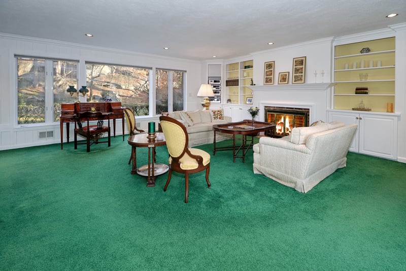 Living room area with wood burning fireplace, built-ins, and wall of windows overlooking private backyard.