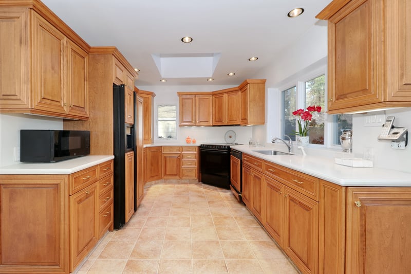Light filled custom kitchen boasts two skylights, tile floor, and wood paneled appliances.