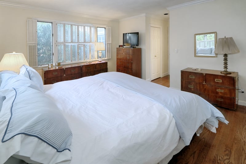 Alternate view of primary bedroom with numerous windows and hardwood floor.