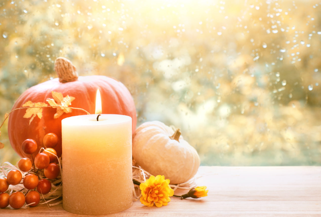 Burning candle, Hokkaido pumpkin and Fall decorations on a windowboard on a rainy day, space for your text
