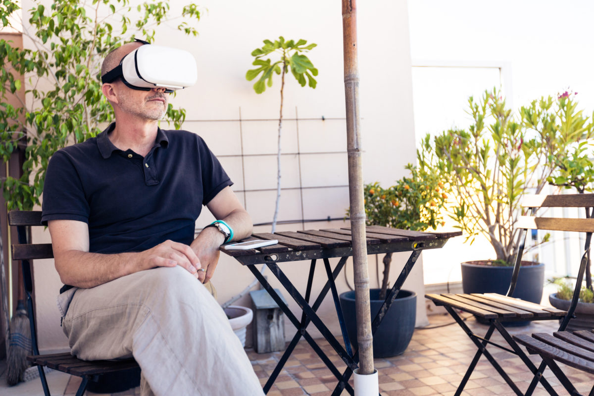 Adult man using VR goggles on his balcony