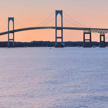 Newport Sunset with Newport Bridge sailboats Newport, Rhode Island, USA. The person in the sailboat is in silhouette & I also changed the shape of the face, body, color of clothing, and hair.